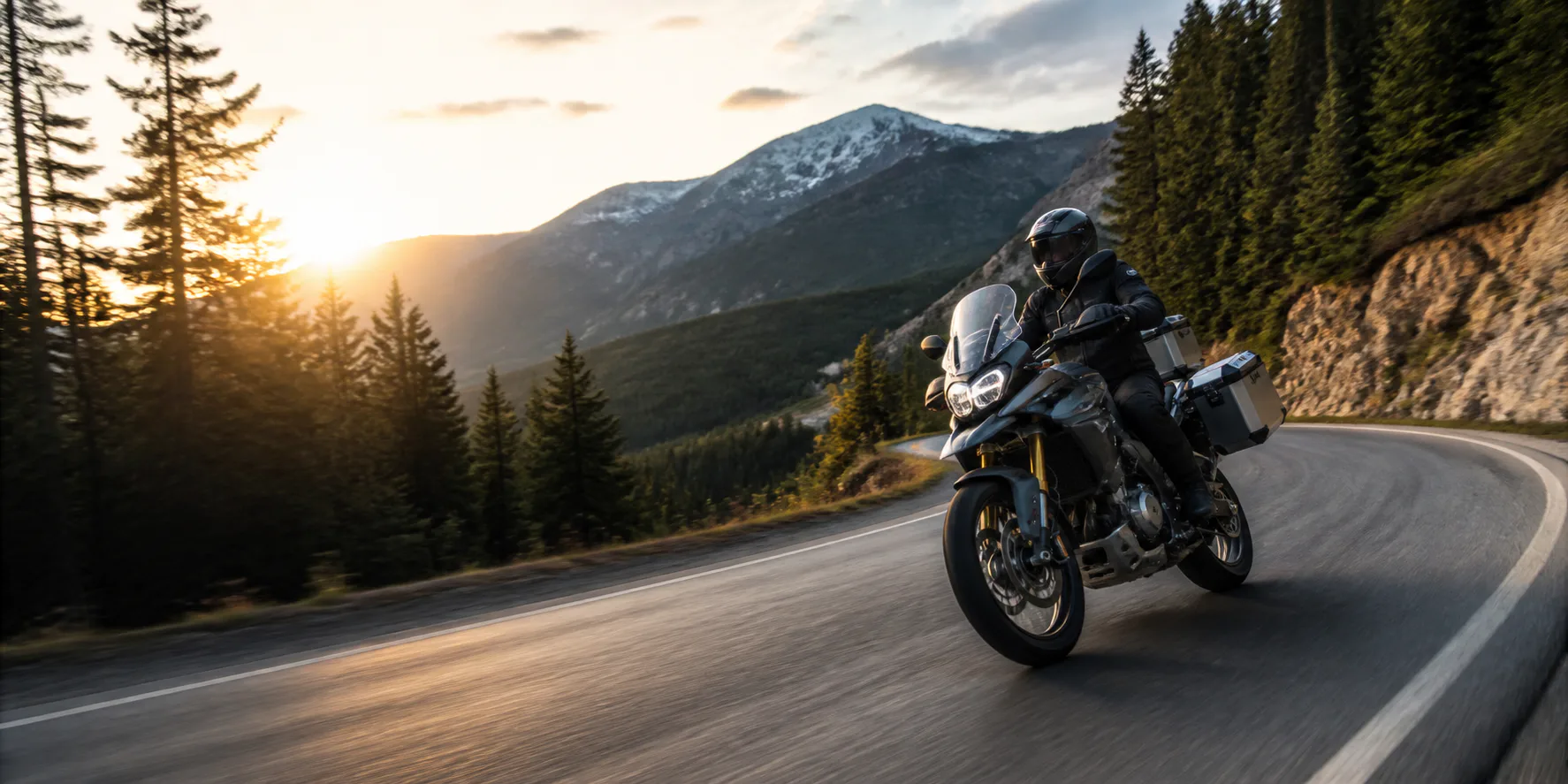 Adventure motorcycle rider traveling through a mountain road at sunrise